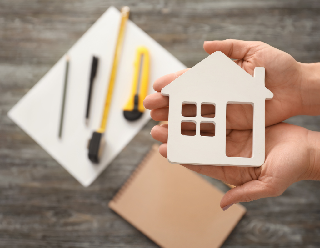 man holding wooden house demonstrating fixing up the house
